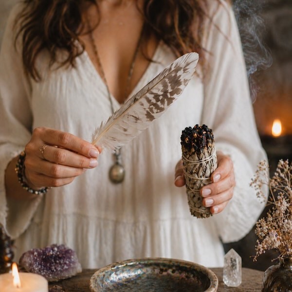 Hvid salvie smudging ritual med fjer til energirensning og spirituel balance