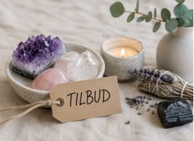 Tilbud p� krystaller og spirituelle produkter med ametyst, rosenkvarts, salvie og levende lys i rolig naturlig stemning.