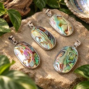 Fire unikke abalone-vedh�ng med farveskinnende perlemor i s�lvindfatning, arrangeret p� natursten med gr�nne planter.