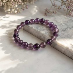 �gte ametyst armb�nd med blanke lilla perler fotograferet p� en elegant marmoroverflade med bl�d naturlig belysning.