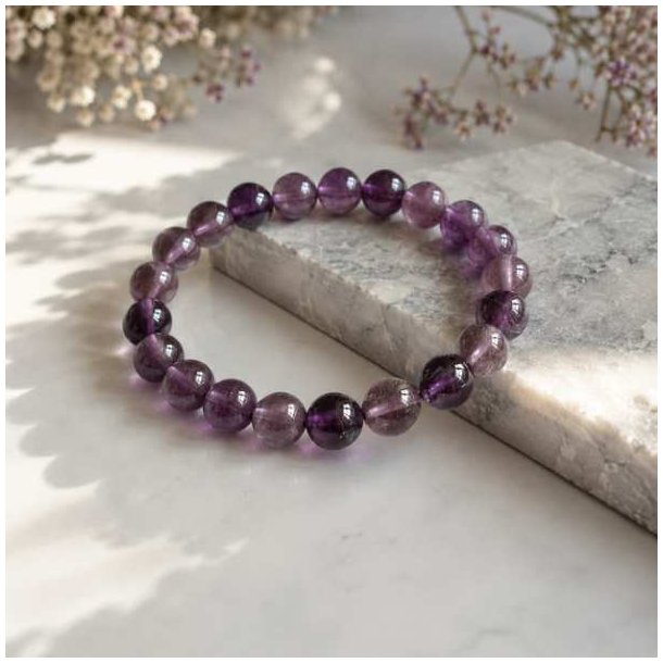 �gte ametyst armb�nd med blanke lilla perler fotograferet p� en elegant marmoroverflade med bl�d naturlig belysning.