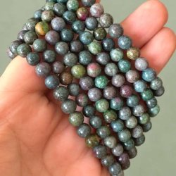 Rubin-safir-stenperler i gr�nne, bl�lige og violette nuancer vist t�t p� i h�nden.