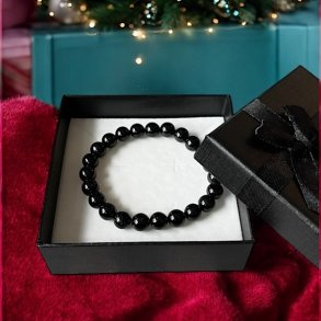 Armbnd i sort turmalin der ligger i en gaveske