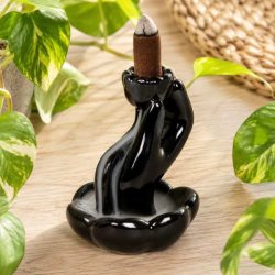 Sort backflow r�gelsesholder i glaseret keramik med r�gelseskegle omgivet af gr�nne planter.