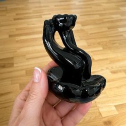 Backflow r�gelsesholder i sort glaseret keramik vist i h�nden for at illustrere st�rrelsen.