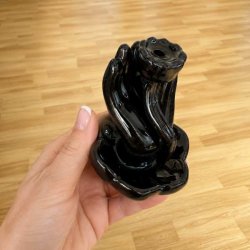 Sort backflow r�gelsesholder i glaseret keramik holdt i h�nden, s� st�rrelsen fremg�r tydeligt.