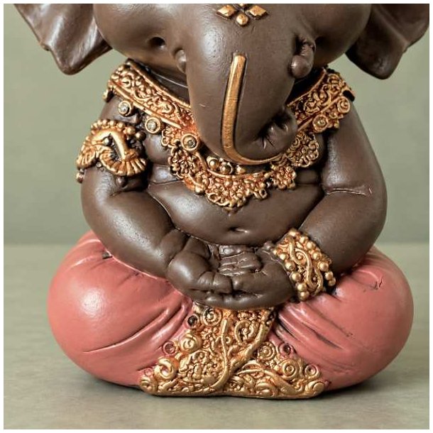 N�rbillede af m�rkebrun Ganesha figur i meditativ stilling, der viser detaljerne i den rosa kl�dedragt og elefantgudens h�nder.
