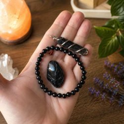 Sort turmalin armb�nd med 6 mm perler, vedh�ng i orgonit-stil og grovpoleret sort turmalin vist i h�nden.