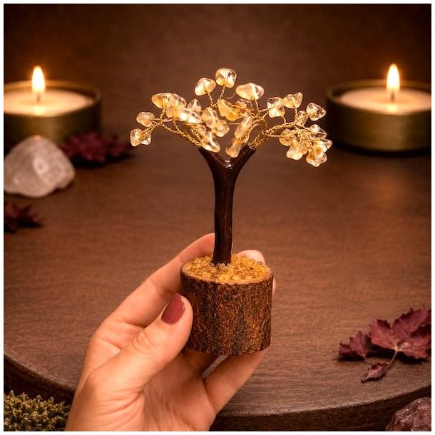 H�nd holder citrin krystaltr� p� naturlig tr�base foran varm og stemningsfuld baggrund.