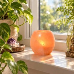 H�ndpoleret Himalaya salt fyrfadsstage i vindueskarm med gr�nne planter og naturligt dagslys.