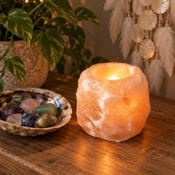 T�ndt orange Himalaya salt fyrfadsstage, der str�ler med et varmt, gyldent lys p� et m�rkt tr�bord i et hyggeligt rum.