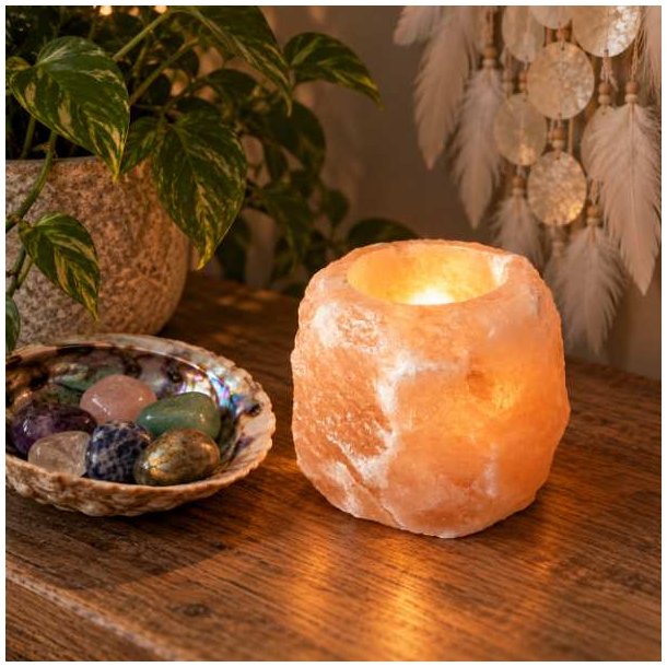 T�ndt orange Himalaya salt fyrfadsstage, der str�ler med et varmt, gyldent lys p� et m�rkt tr�bord i et hyggeligt rum.