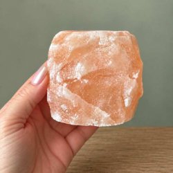Firkantet lyser�d Himalaya saltkrystal lysestage, der holdes i en h�nd for at vise den naturlige struktur og overflade.
