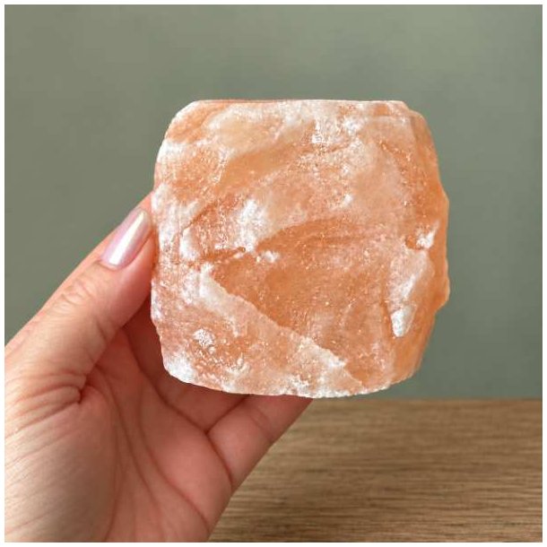 Firkantet lyser�d Himalaya saltkrystal lysestage, der holdes i en h�nd for at vise den naturlige struktur og overflade.