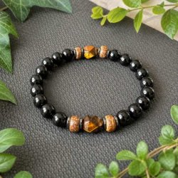 Unisex armb�nd med 10 mm sorte onyxperler, gyldent tiger�je, h�matit og tr� fotograferet i naturlige omgivelser