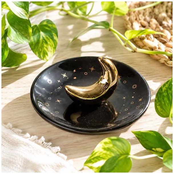 R�gelsesholder med gylden m�ne og stjerner i glaseret keramik med r�gelsespinde p� tr�bord i hyggelige omgivelser.