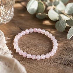 �gte rosenkvarts armb�nd med 6 mm krystalperler fotograferet p� et rustikt tr�bord i naturligt dagslys.