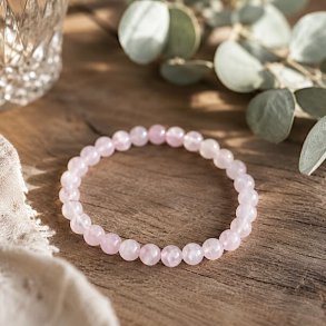 �gte rosenkvarts armb�nd med 6 mm krystalperler fotograferet p� et rustikt tr�bord i naturligt dagslys.