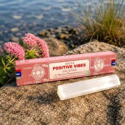 Satya Positive Vibes h�ndrullede r�gelsespinde 15 g p� natursten ved siden af en selenitstav, som symboliserer positiv energi og harmoni.