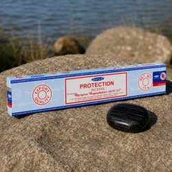 Satya Protection h�ndrullede r�gelsespinde 15 g p� natursten ved siden af en sort sten.