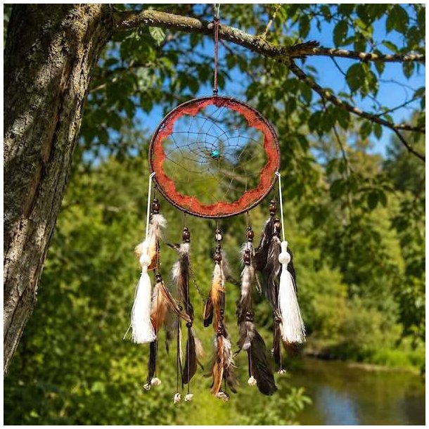 Unik h�ndlavet shaman dr�mmefanger med fjer, kvaster og turkis sten h�ngende i et tr� i natursk�nne omgivelser.