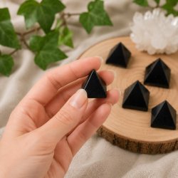 Lille sort turmalin pyramide i h�nden ca. 2,5-3 cm med naturlig spirituel baggrund og flere pyramider i baggrunden