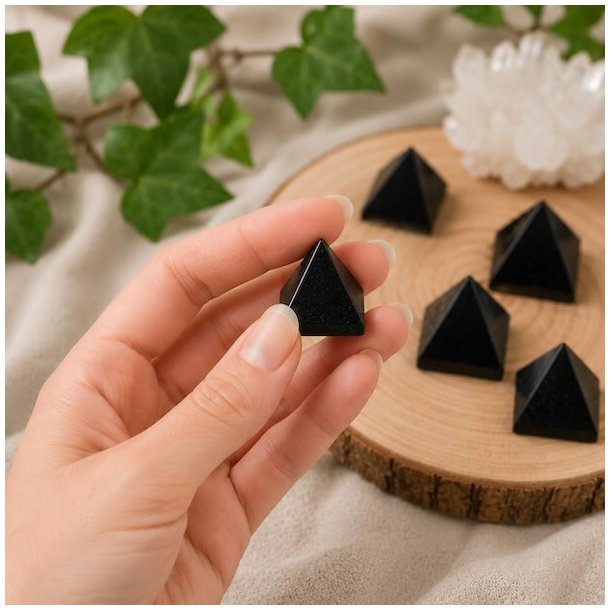Lille sort turmalin pyramide i h�nden ca. 2,5-3 cm med naturlig spirituel baggrund og flere pyramider i baggrunden
