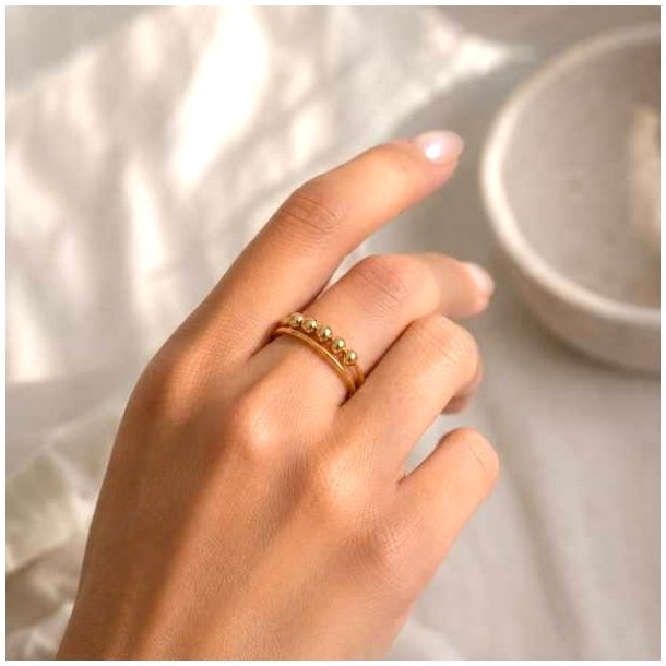 Guldfarvet stressring med flytbare kugler p� finger